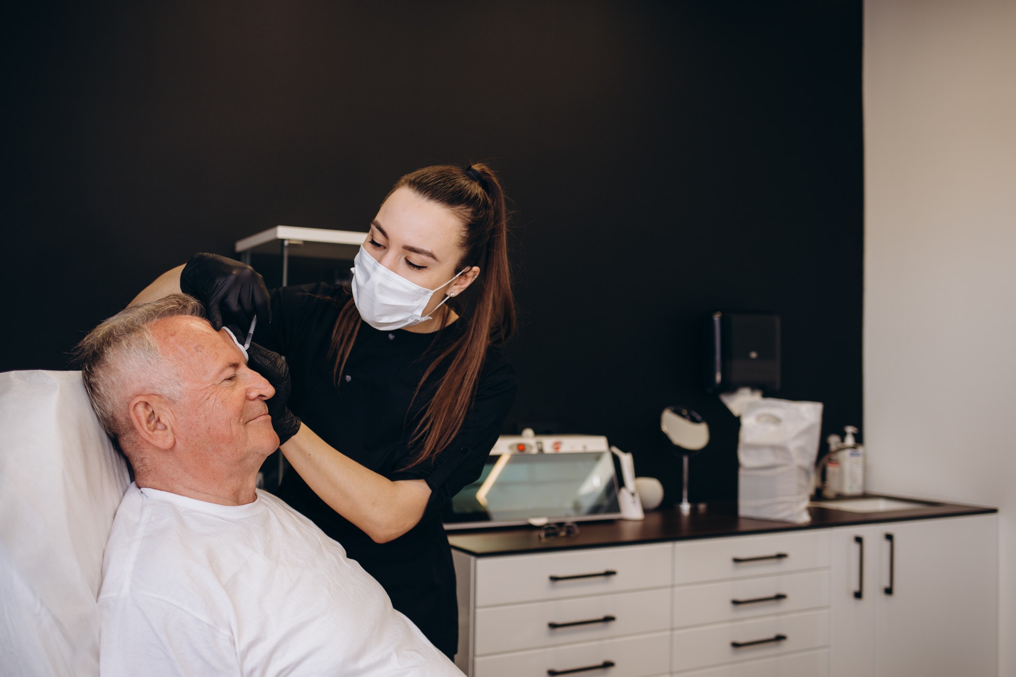 an old man makes an injection for wrinkles in a beauty salon