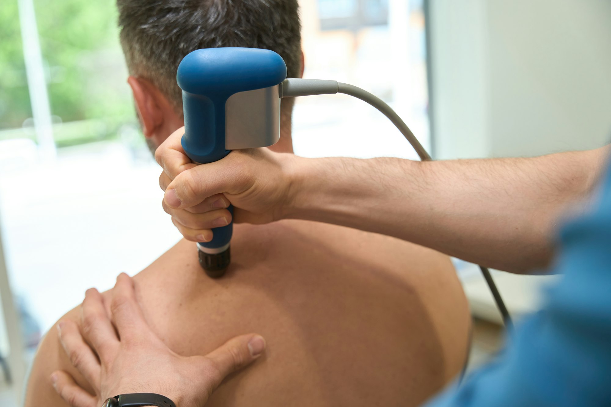 Qualified physical therapist doing ESWT procedure on patient